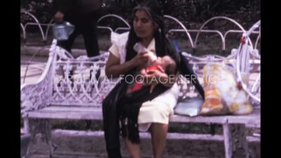 Mexico 1970s, Woman feeding milk to a child sitting on a bench