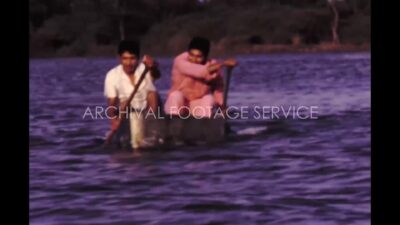 Mexico 1970s, Two man riding boat in river beside forest