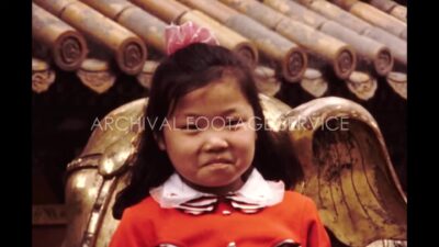 China 1980s, A little girl smiling in front of statue during daytime