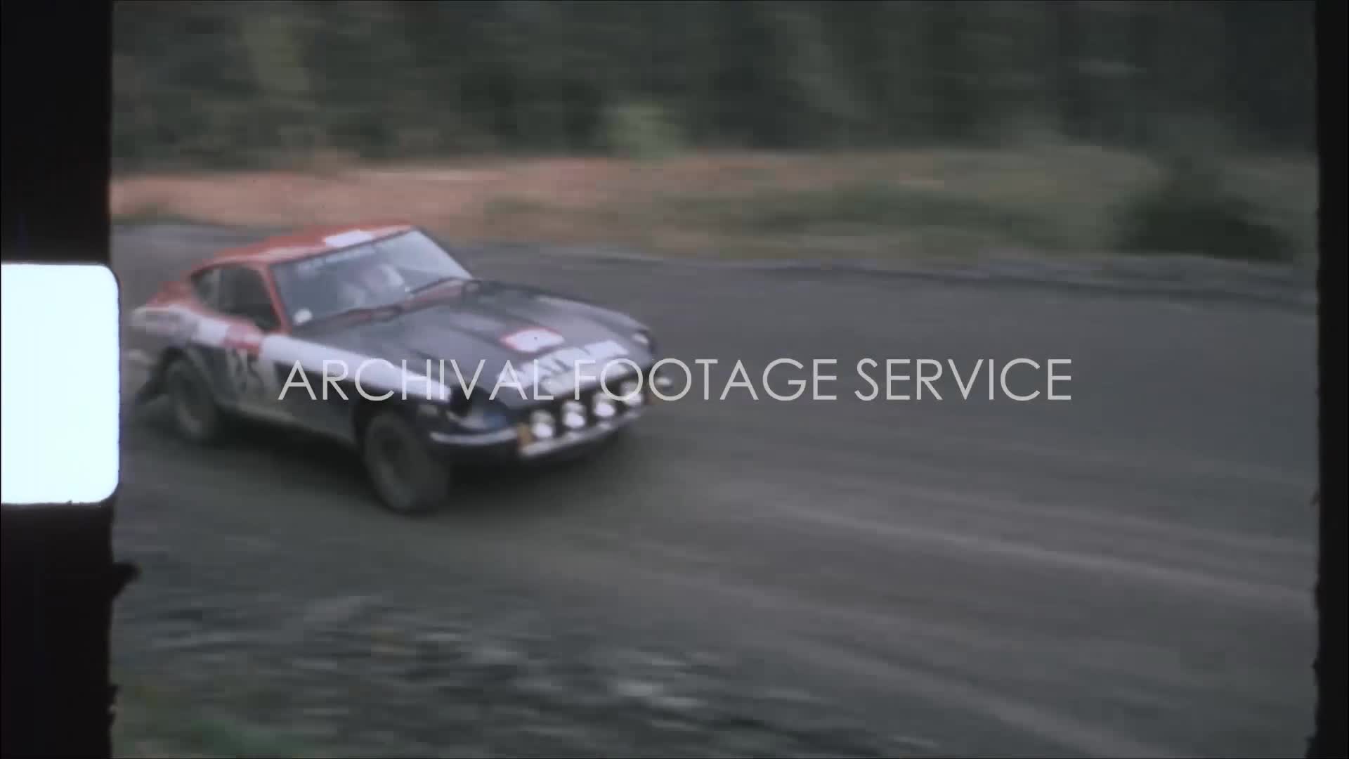 England 1970s, Datsun 240Z rally car speeding through forest road ...